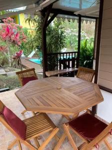 a wooden table and chairs on a patio at Bungalow accueillant à Le Diamant avec piscine partagée in Le Diamant