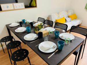 a dining room table with white plates and chairs at Hana Home - New Cozy House with 4 bedrooms - 10min from Umeda in Osaka