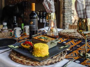 un piatto di cibo su un tavolo con una bottiglia di vino di Grace of Africa, Couples 5 STAR Nature Lodge a Marloth Park