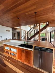 a large kitchen with wooden cabinets and a sink at Refugio Monteverde house, privacy & ocean view! in Monteverde Costa Rica +33 photos