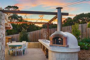 a patio with a pizza oven with a table and chairs at LUXE POINT in Blairgowrie