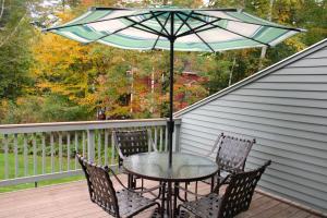 a table and chairs on a deck with an umbrella at The White Mountain Escape in Woodstock