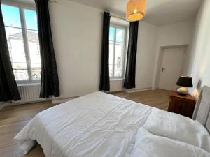 a bedroom with a large white bed and two windows at Saint Goustan à pied! Joli appartement 2p in Auray