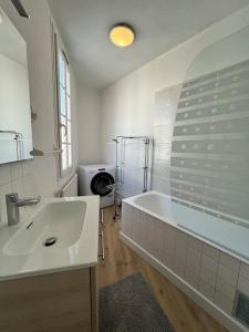 a white bathroom with a tub and a sink at Saint Goustan à pied! Joli appartement 2p in Auray +4 photos