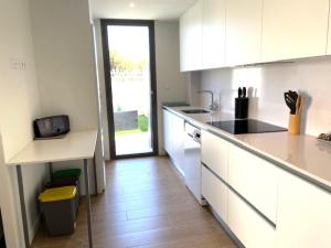 a kitchen with white cabinets and a wooden floor at Denia Apartment Rental - Vivir La Vida in Denia