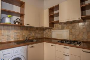 a kitchen with white cabinets and a sink and a washer at Villetta Mare Blu With Pool, Country Village, Stintino in Cuile Pazzoni +9 photos