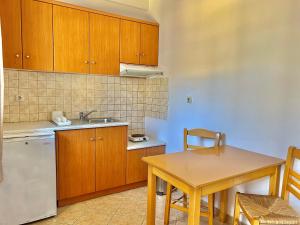 a kitchen with wooden cabinets and a table and a sink at Marinos Studios and Apartments in Gialiskari