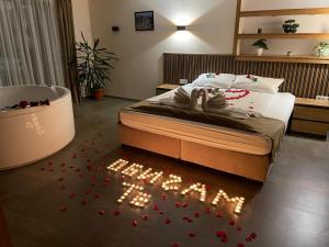 a bedroom with a bed and a tub with red flowers on the floor at Къща Александра 2 in Dobrinishte