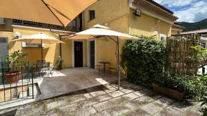 a patio with umbrellas and chairs and a building at Casa Santicelli - Room in Maratea