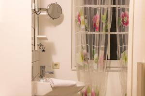 baño con lavabo y cortina de ducha con flores rosas en Tasca im Feui Apartments, en Stuttgart