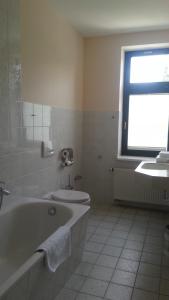 baño con bañera, aseo y ventana en Teichhotel, en Schmalkalden