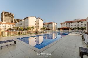 una piscina con panchine e edifici sullo sfondo di Apto c/ Piscina a 350m da Praia VJGM0102 a Cururupe