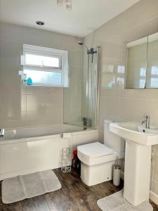 a bathroom with a sink and a tub and a toilet at Heathbrook House in Cardiff
