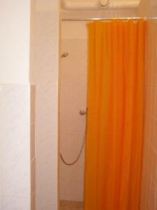 y baño con ducha y cortina de ducha de color naranja. en Hostel Praha Ládví, en Praga