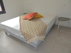 ein Bett mit zwei Kissen und einer Decke darauf in der Unterkunft Villa neuve à 900 m de la plage in Santa-Lucia-di-Moriani