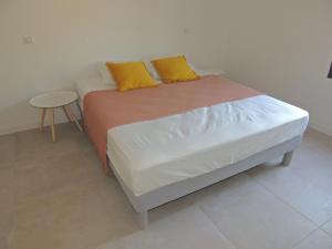 ein Bett mit zwei gelben Kissen auf einem Zimmer in der Unterkunft Villa neuve à 900 m de la plage in Santa-Lucia-di-Moriani