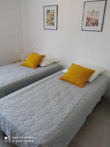 2 Betten mit gelben Kissen in einem Zimmer in der Unterkunft Villa neuve à 900 m de la plage in Santa-Lucia-di-Moriani