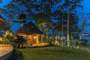 a small hut with a thatched roof at night at De Rain Eco Beach Resort in Entebbe
