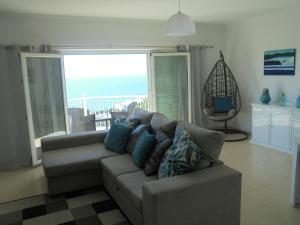 a living room with a couch and a view of the ocean at Ericeira Sunset Apartment in Ericeira