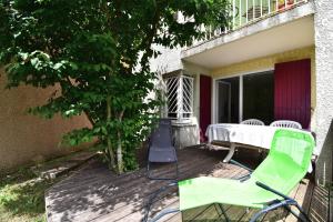 a green chair and a table on a deck at Escapade Provençale - T2 avec cuisine et terrase privée in Digne-les-Bains