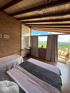 a bedroom with two beds and a large window at Chacrinha pousada e restaurante in Caldas