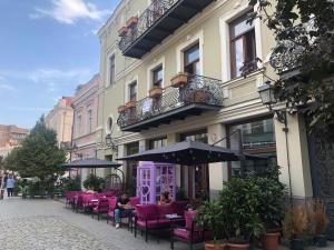 Un grupo de sillas rosas y una sombrilla frente a un edificio. en Apartments MARGARITA, en Tiflis
