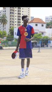 un joven parado en un campo con un guante de béisbol en La ville, en Dakar