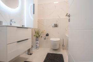 a white bathroom with a toilet and a sink at KARINA APARTMAN in Dunajská Streda