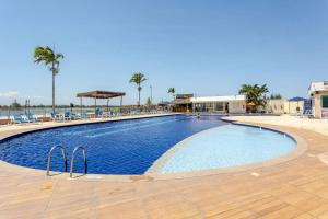 a large swimming pool with chairs and palm trees at Apto 1 quarto no Golden Lake! in Arraial do Cabo