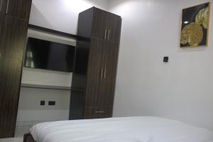 a bedroom with a bed and a cabinet with a television at The Vistana 4Bedroom Pearly Gate Estate Ikota VGC Lekki in Igboshere