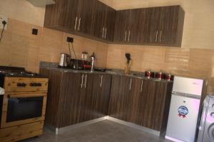 a kitchen with wooden cabinets and a white refrigerator at The Vistana 4Bedroom Pearly Gate Estate Ikota VGC Lekki in Igboshere