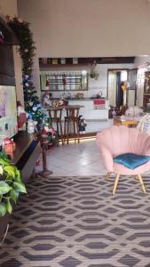 a living room with a pink chair and a christmas tree at Quarto da Tati in Garopaba