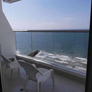 zwei Stühle vor einem Fenster mit Meerblick in der Unterkunft Lodging Apartamento 1 Frente a la Playa in Cartagena de Indias