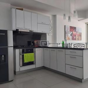 eine Küche mit weißen Schränken und einem Herd mit Backofen in der Unterkunft Lodging Apartamento 1 Frente a la Playa in Cartagena de Indias