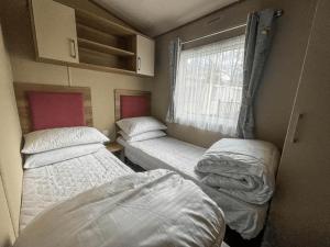 two beds in a small room with a window at Marie Helene, 58 Mallard Carlton Meres Holiday Park in Kelsale +22 photos