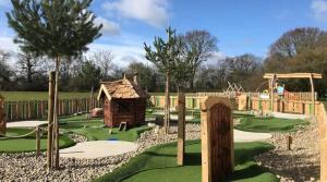 a playground with a mini golf course and a wooden house at Marie Helene, 58 Mallard Carlton Meres Holiday Park in Kelsale