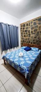 een slaapkamer met een bed met een blauw-witte deken bij Chalé do corisco in Paraty