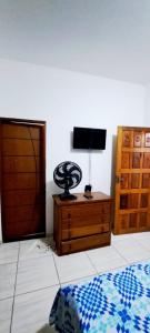 een slaapkamer met een bed, een ladekast en een televisie bij Chalé do corisco in Paraty
