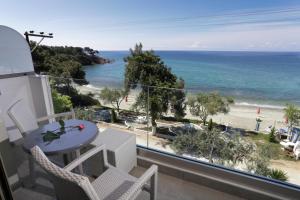 een balkon met een tafel en stoelen en uitzicht op het strand bij Hotel Akti in Pefkari