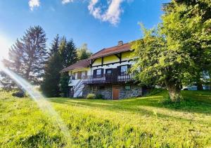 a large house on a grassy field with a tree at Chata Rychnovanka in Zdobnice