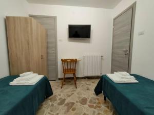a room with two beds and a chair and a television at La terrazza sui Nebrodi in Mistretta