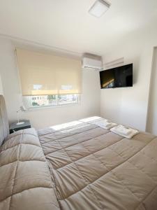 a large bed in a white room with a large bedspread at Saavedra 118 1°H by depptö in Bahía Blanca