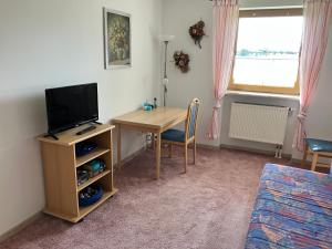 a room with a desk with a television and a table with a chair at Ländliche Wohnung bei Buchenberg im Allgäu in Buchenberg