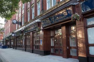 uma fila de lojas numa rua da cidade com um edifício em The Furness Railway Wetherspoon em Barrow in Furness