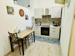 eine kleine Küche mit einem Holztisch und Stühlen in der Unterkunft MaxMondello in Palermo