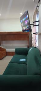 a living room with a green couch and a flat screen tv at EstanciaS ALELI norte Vipasa entr salida aerprto terml de tte base aérea MFS C eventos valle del Pacífic orquideorama in Cali +1 photo