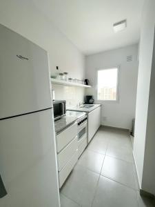 a white kitchen with white appliances and a window at Saavedra 118 2°C by depptö in Bahía Blanca
