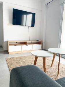 a living room with two tables and a flat screen tv at Saavedra 118 2°C by depptö in Bahía Blanca