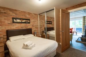 a bedroom with a large bed with towels on it at Farley, woodland lodge with hot tub for 8 in Oakamoor