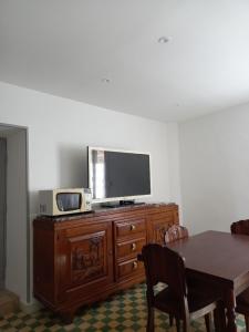 a television on top of a wooden dresser with a table at Appartement St Jacques in Saint-Gervais-sur-Mare